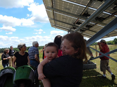 Mom and baby in the foreground, crowd of people at solar farm opening, pre-pandemic