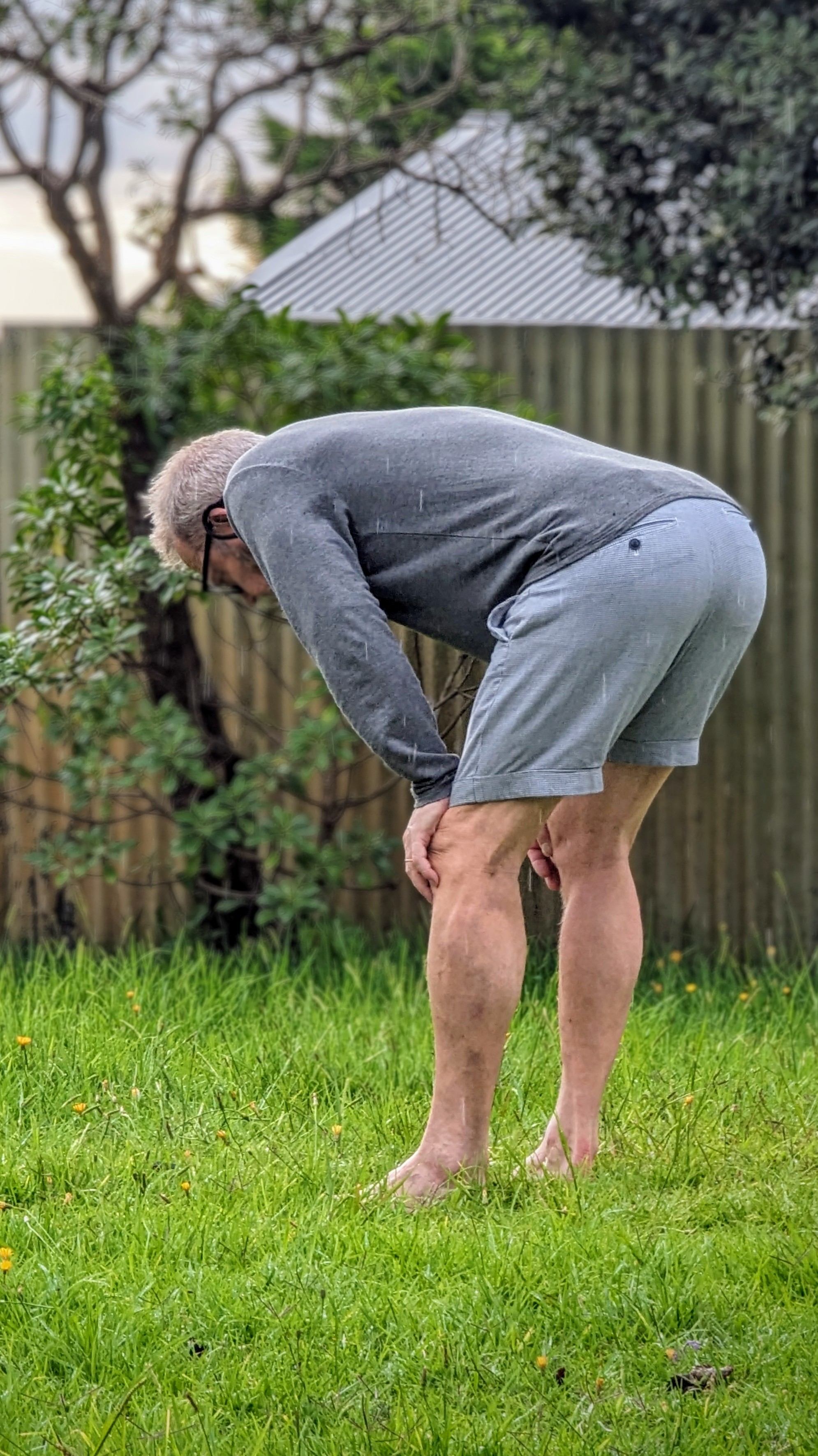 Bent over man on a lawn looking intently down