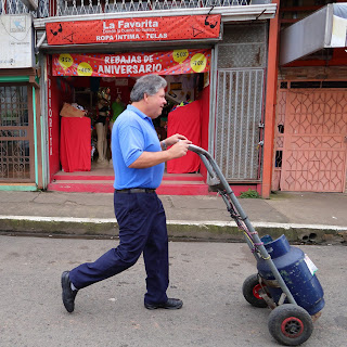 Man rolling dolly with gas tank in Puriscal.