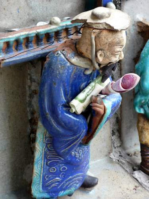 Detail of a ceramic frieze atop the Dragon Mother's Temple, Guang Dong Province, China. People lean over the upper balcony to tuck money into the sculptures to help lubricate the passage of their wishes to reality.