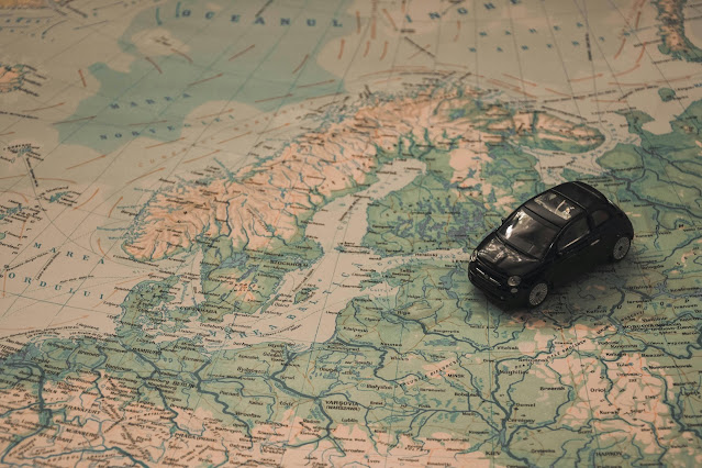 Black toy car placed on a vintage map of Europe, symbolizing international car rental and road trip planning