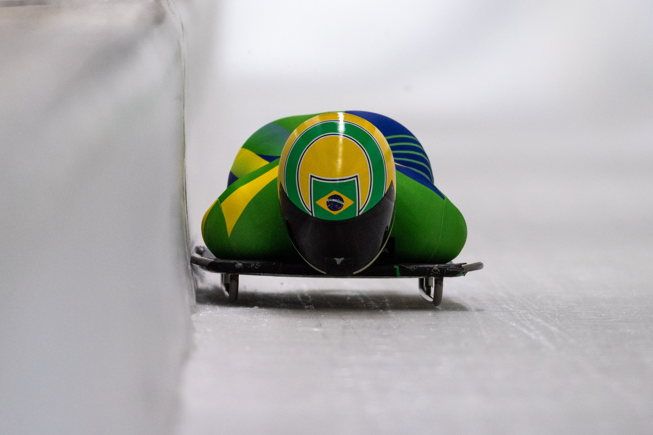 Nicole Silveira, com roupa verde e amarela e capacete amarelo, desce pista de gelo para Copa do Mundo de Skeleton