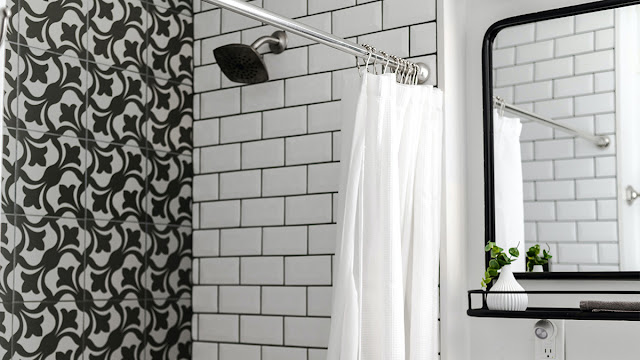 Black and white bathroom with shower and small vanity.