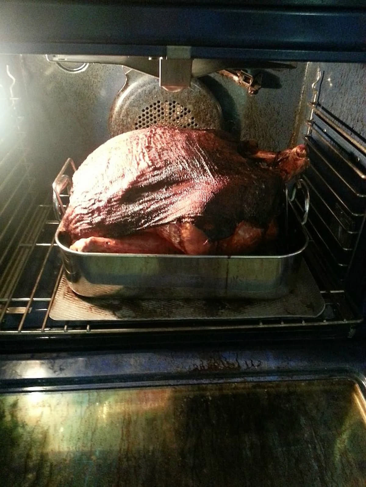 Cheesecloth Turkey that is done roasting in the oven with the oven door open.