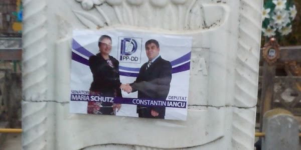Afiș electoral cu doi candidați PPDD lipit pe un mormânt dintr-un cimitir din Calafat