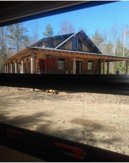 Log cabin home under construction, as seen through an RV window