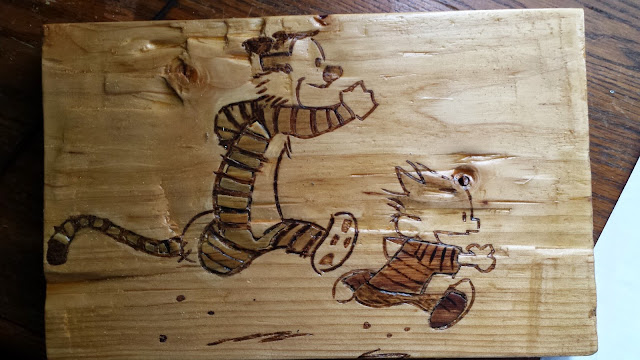 Wood carving depicting Bill Watterson's Hobbes chasing Calvin