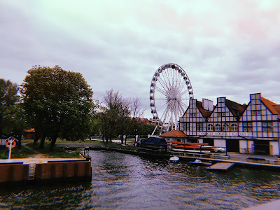 big wheel and some buildings on the waterfront in Gdansk with some trees and a grey sky