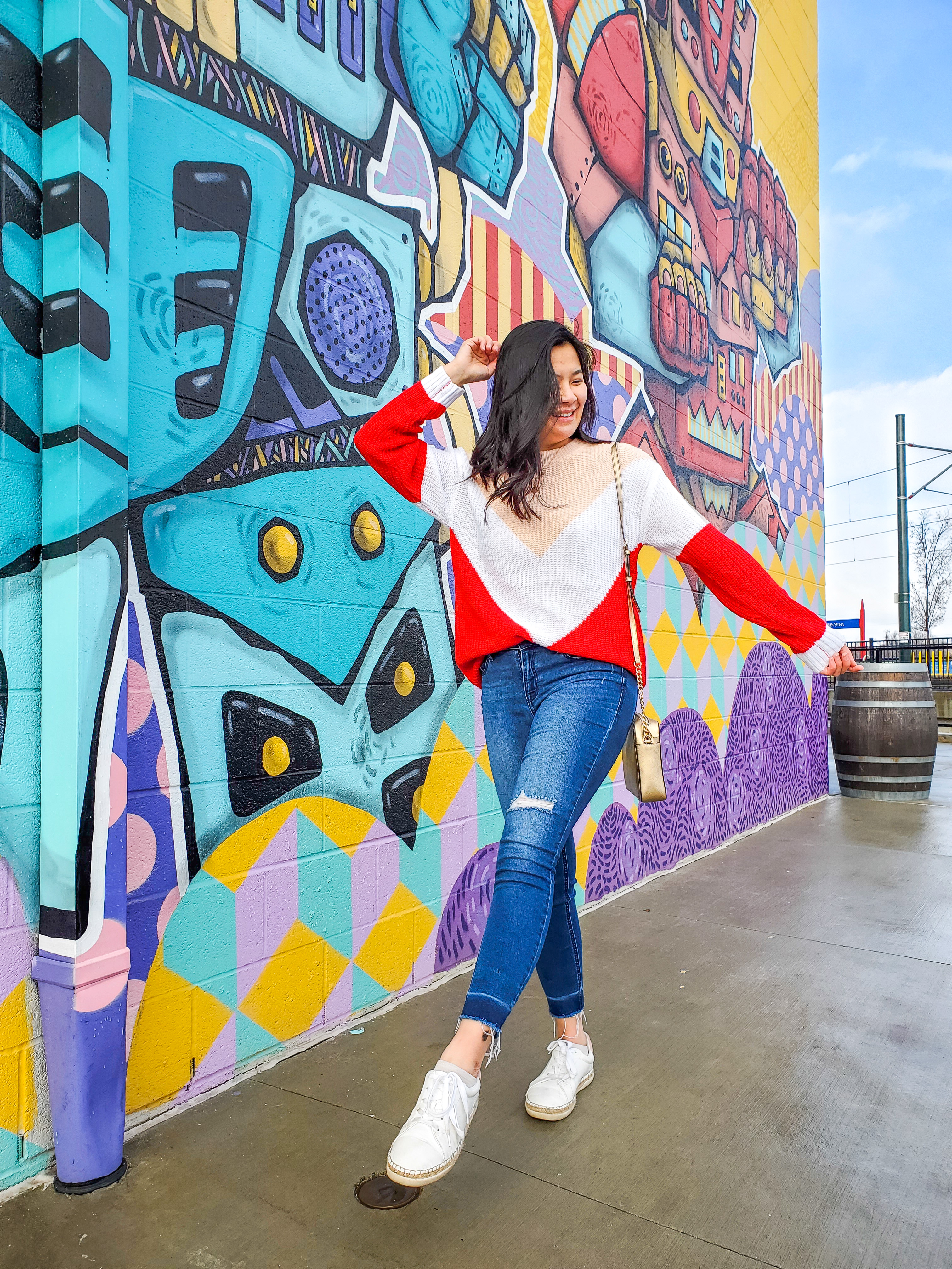 Red and pink color block sweater styled in front of a colorful mural