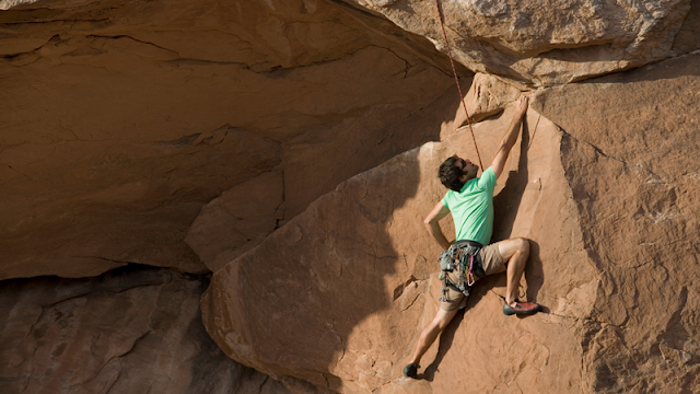 a top rope climber on a nearly flat rock face
