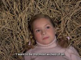 A girl laying on a bed of straw. Subtitle "I want to be the most wicked of all" This is a screenshot from the movie Poison for the Fairies.