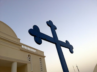 Kreuz vor einer Kirche - in Griechenland ist der christliche Glaube nach wie vor sehr wichtig