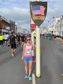 Me in my USA flag running outfit posting next to a plaque on a flag pole with the USA flag on it.