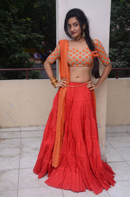 Janani Reddy in orange traditional wear, showcasing a cute navel.