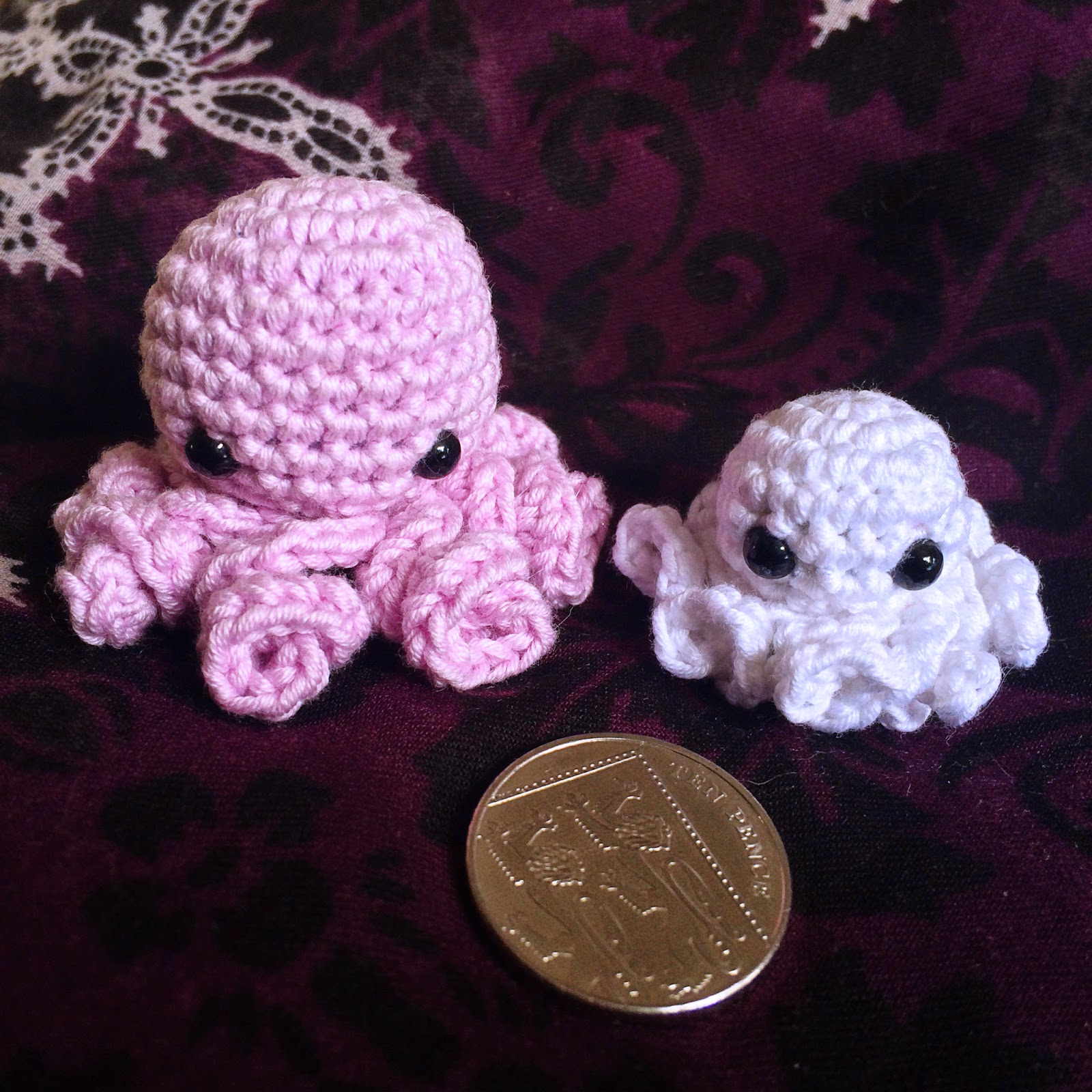 two tiny crochet ocotopus amigurumis with coin