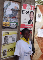 A Zimbabwean woman and campaign posters of the three presidential candidates