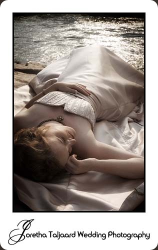 Bride lying on rocks next to brook