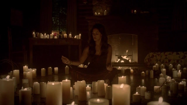 Screenshot of a witch from The Vampire Diares surrounded by at least fifty white pillar candles.