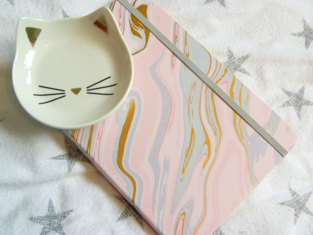 A white and gold cat trinket dish, and a colourful notebook