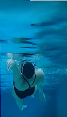 Image of a woman doing Backstroke. Viewed from below the water. Fix Those bent elbows with better body rotation.