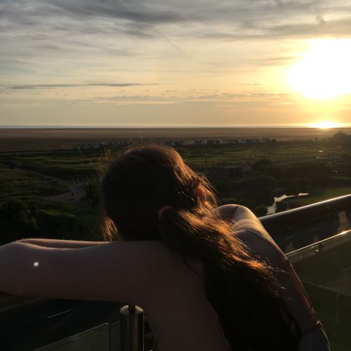 girl looking out over balcony to sunset