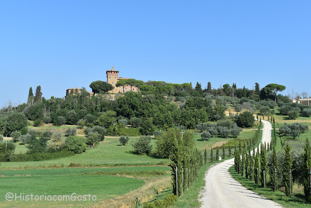 foto da entrada de Pienza com uma estradinha de terra e cercada de Ciprestes