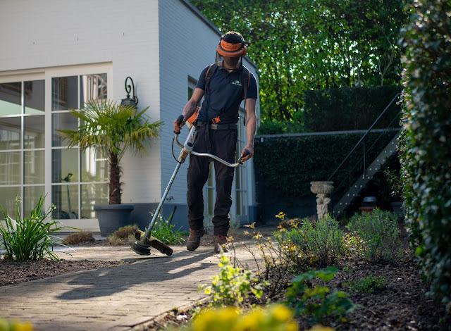 Man with strimmer in garden:Photo by Boris Debusscher on Unsplash