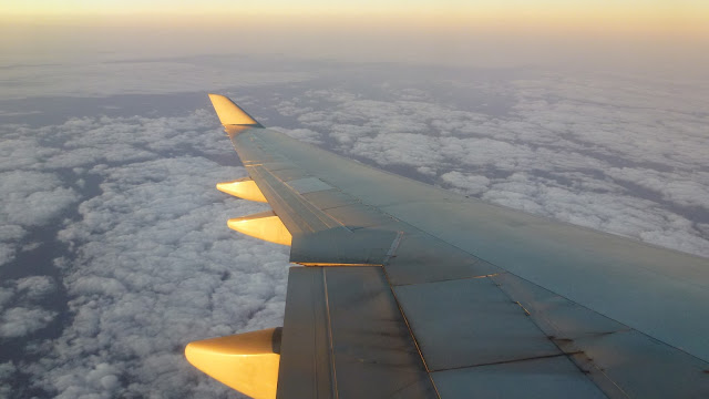 Wing of the aircraft dipping toward the clouds