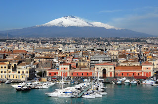 The port city of Catania, the second largest city in Sicily, with a snow-capped Etna in the distance