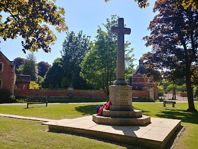 Photograph of the north side of the war memorial with the Octagon Lodge of North Mymms Park in the background. Image by the North Mymms History Project released under Creative Commons