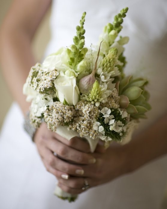 The bride's bouquet has some white roses and green cactus flowers for a