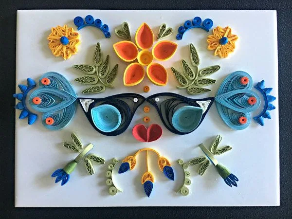 two quilled birds and blue, yellow, orange floral arrangement