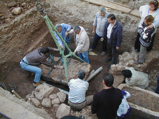 Η ανύψωση της καλυπτήριας πλάκας του πήλινου κρατήρα και του χάλκινου λέβητα όπου φυλάσσονταν οι πίνακες.