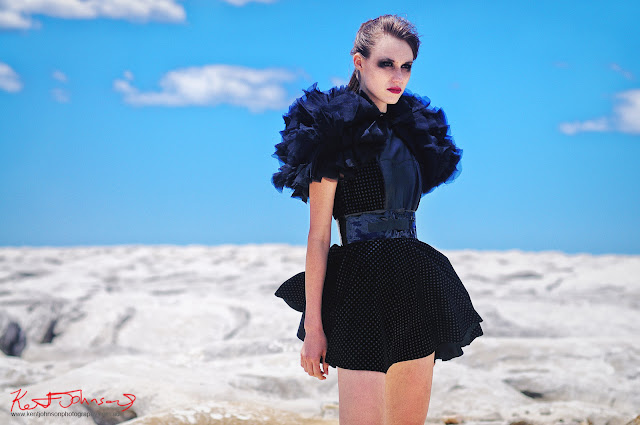 Fashion model in a textured black dress with ruffled sleeves, photographed in moonscape location for a magazine submission editorial - The Girls Who Fell To Earth, by photographer Kent Johnson.