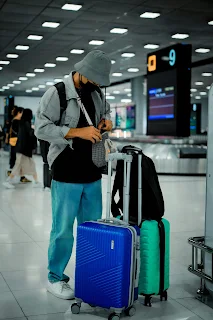Homme voyageur à l’aéroport préparant son voyage avec ses bagages à roulettes