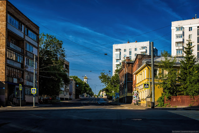 Городская улица с домами по бокам и церковью на фоне