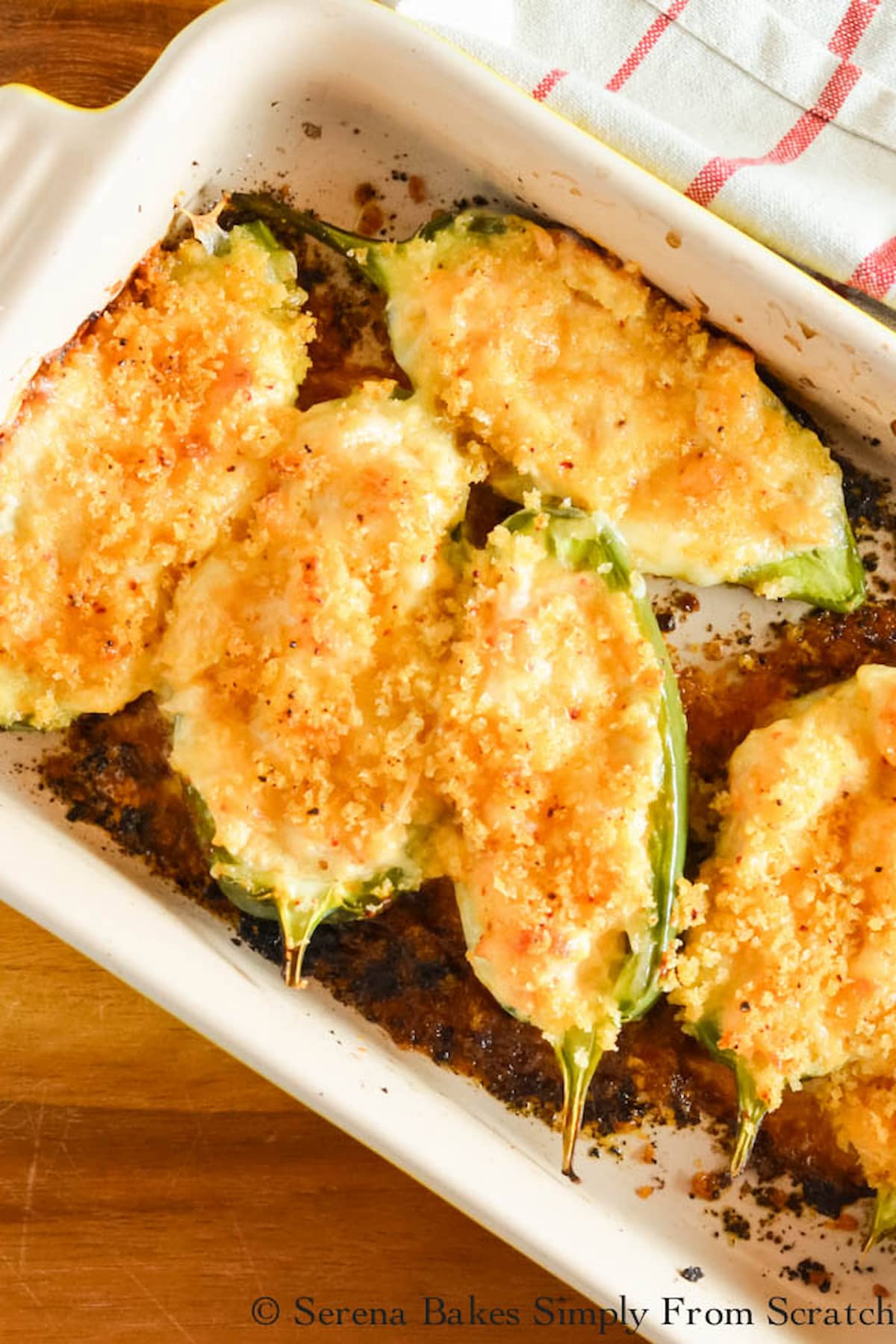 Shrimp Stuffed Jalapeno Poppers topped with panko bread crumbs baked in a small baking dish on a wooden cutting board.