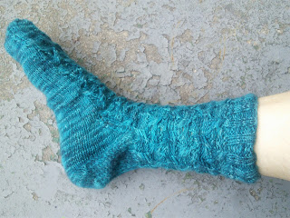 a blue sock with a slip-stitch cable pattern on the leg and instep