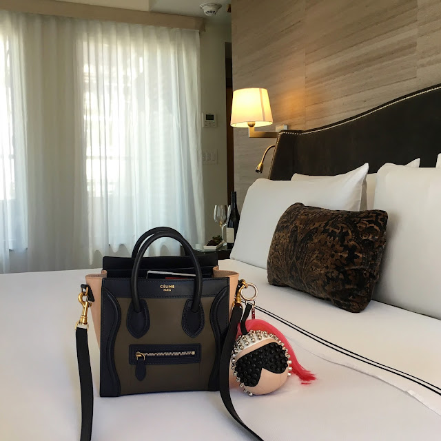 Celine Tricolor Taupe Olive and Anthracite Nano bag with Fendi Karlito Karl Lagerfeld bag bug charm, atop a bed at The Quin hotel