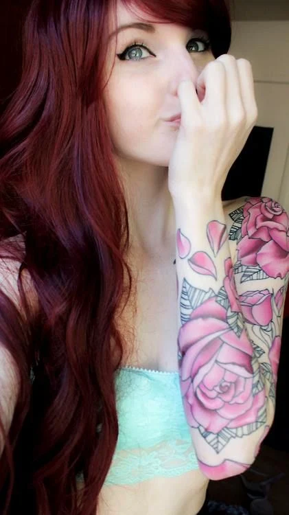 Linda peliroja con tatuajes de flores rosas en su brazo