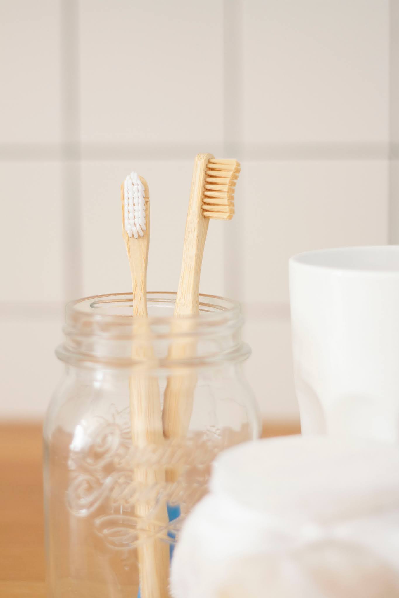 two bamboo toothbrushes in a mason jar