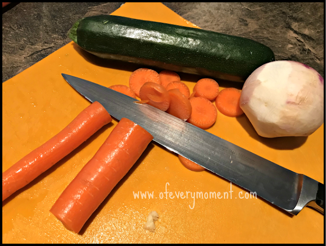 A cutting board and chef's knife with vegetables