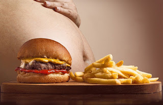 Picture of overweight man behind a burger and fries