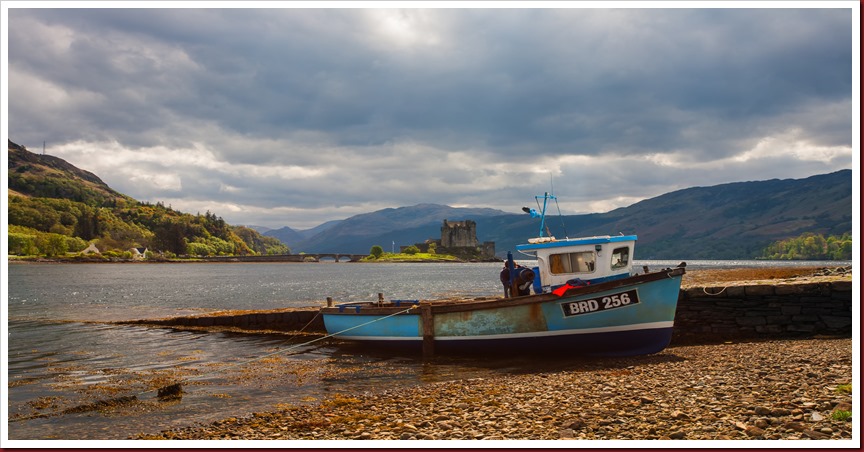 A small Lochalsh fishing boat with Eilean Donan Castle in the background Photo of A small Lochalsh fishing boat with Eilean Donan Castle in the background