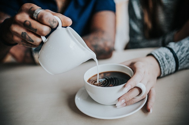 sedang menuangkan susu ke kopi