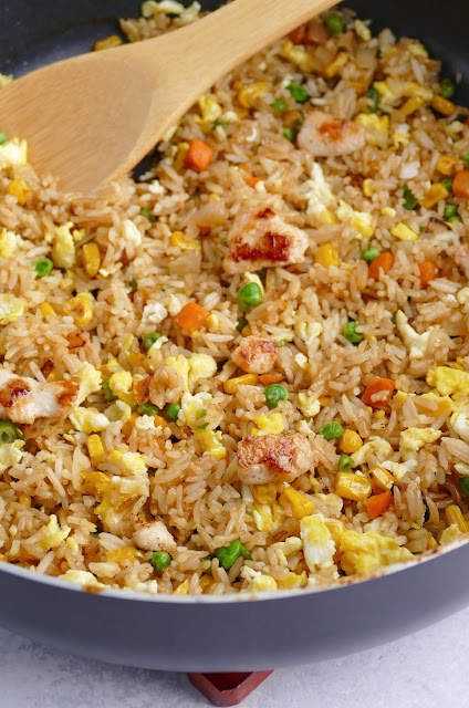 rice in a skillet with a bamboo spoon inside.