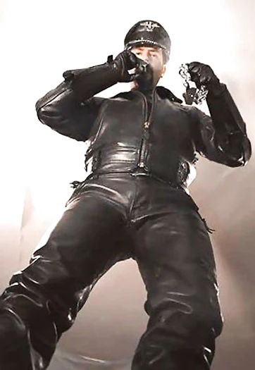 Full geared Leatherman standing above with a cigar and mouth holding handcuffs looking down Superior PV