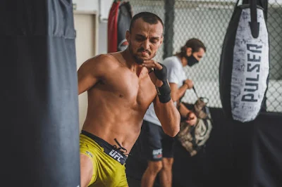 UFC fighter practicing kickboxing on a heavy bag.