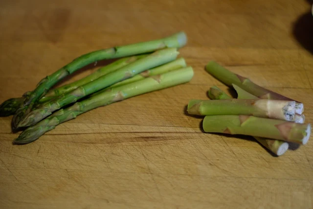 Cutting the woody end off of the asparagus. 