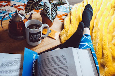 Woman reading in bed with blankets and tea